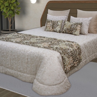 Cama com edredão bege e manta com padrão de folhas em tons terra