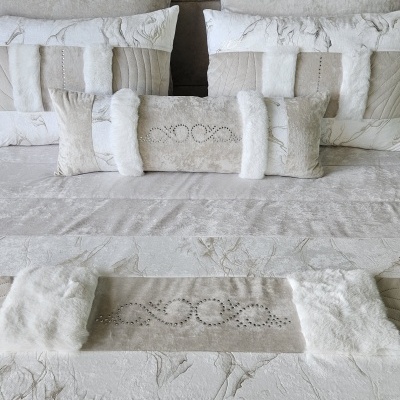 Conjunto de almofadas e manta decorativas em bege e branco com detalhes em cristais.