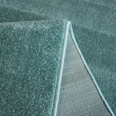 Tapete azul-petróleo com textura felpuda e detalhe da dobra mostrando o avesso.