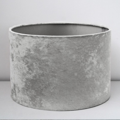 Abajur cylindrical cinzento de veludo amassado sobre superfície branca