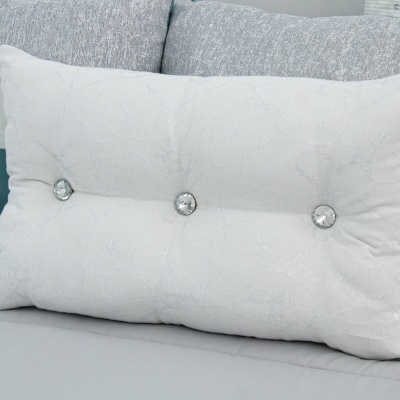 Almofada branca com botões decorativos sobre sofá cinza
