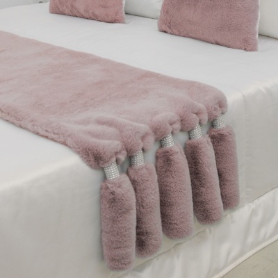 Cobertor e almofadas felpudas cor de rosa sobre cama branca