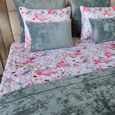 Cama com edredão floral e almofadas de veludo cinza