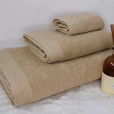 Três toalhas castanhas empilhadas e frasco com varetas aromáticas