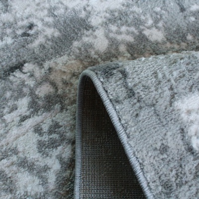 Tapete cinzento com padrão branco e cinza claro, material felpudo, base antiderrapante