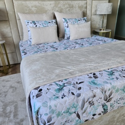 Cama estofada creme com roupa de cama floral e almofadas creme