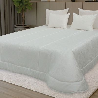Cama com edredão branco e almofadas num quarto com cabeceira cinzenta e planta verde
