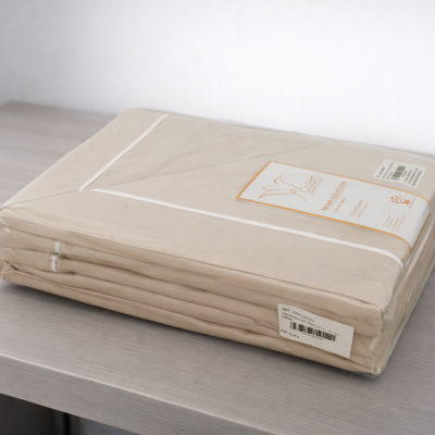 Colcha de cama bege clara embalada em plástico com etiqueta