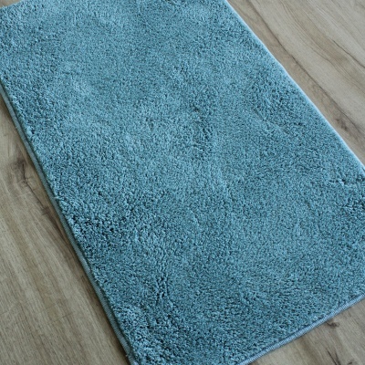 Tapete azul felpudo sobre chão de madeira clara