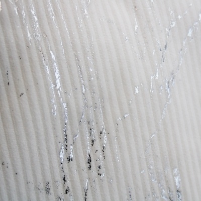 Superfície creme ripada com manchas pretas e textura brilhante