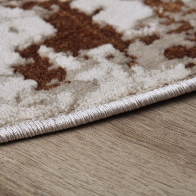 Tapete castanho e creme com textura fofa sobre chão de madeira clara.
