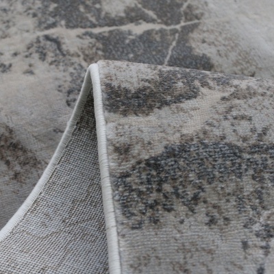 Tapete cinza e bege com padrão abstrato e dobra mostrando o verso