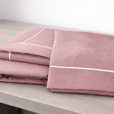 Conjunto de roupa de cama rosa salmão com linhas brancas dobrado sobre mesa