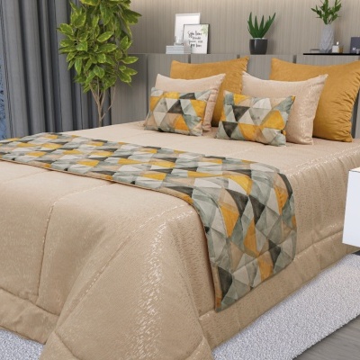 Cama com edredão bege, almofadas bege e amarelas, e manta geométrica colorida