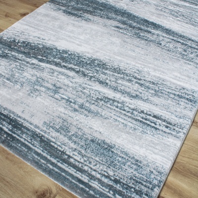 Tapete cinzento e branco com padrão abstrato sobre pavimento de madeira