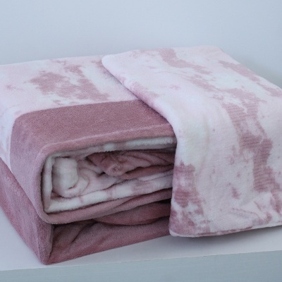 Manta felpuda rosa e branca dobrada numa superfície branca