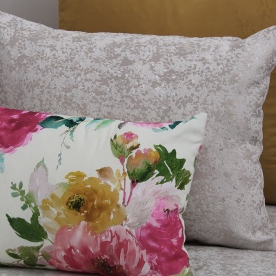 Três almofadas decorativas com padrões florais, textura abstrata e cor lisa mostarda.
