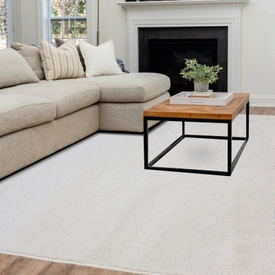 Sala com sofá bege, mesa de madeira e tapete branco