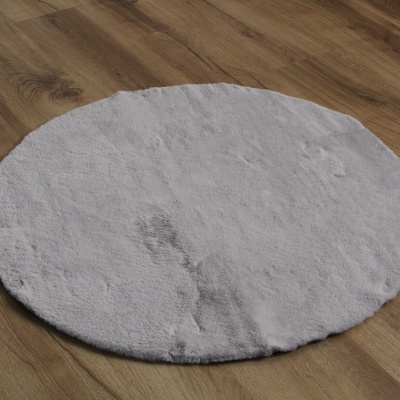 Tapete redondo branco com manchas sobre chão de madeira clara