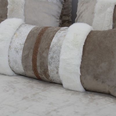 Almofada retangular com faixas brancas e castanhas sobre superfície clara