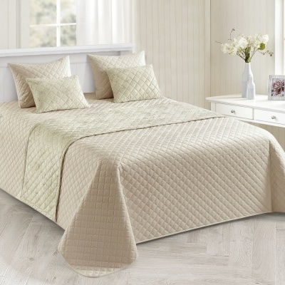 Conjunto de cama bege matelassê com almofadas em quarto iluminado