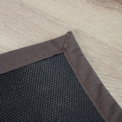 tapete ou almofada preta com borda castanha sobre chão de madeira