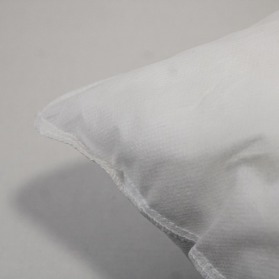 Canto de almofada branca com costura visível sobre superfície cinzenta