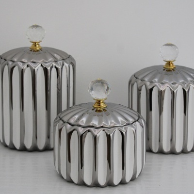 Três frascos metálicos prateados com tampas e puxadores de bola transparente