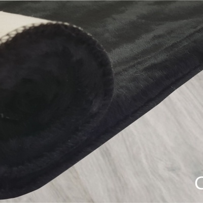 Tapete preto enrolado com etiqueta dourada sobre chão de madeira cinzenta