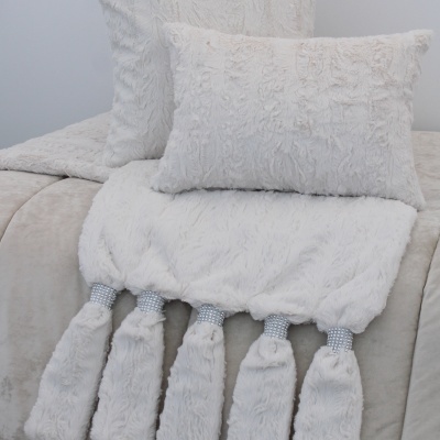 Almofadas e manta brancas peludas com tasséis decorativos e detalhes prateados