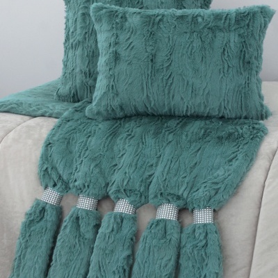Almofadas e manta felpudas azul esverdeado com pompons decorativos e faixas brilhantes