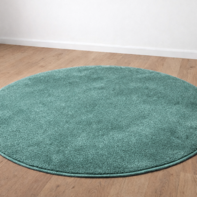 Tapete redondo verde água sobre chão de madeira clara