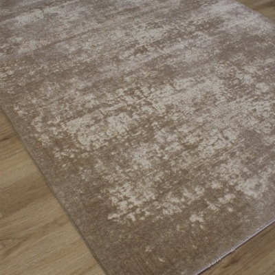 Tapete bege e castanho claro com padrão abstrato sobre chão de madeira.