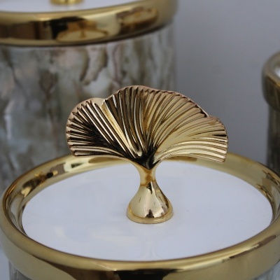 Frasco decorativo com tampa branca e detalhes dourados com alavanca em forma de folha