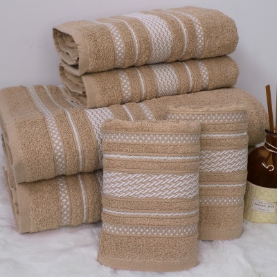 Conjunto de toalhas bege com riscas brancas e difusor de aroma castanho com pauzinhos