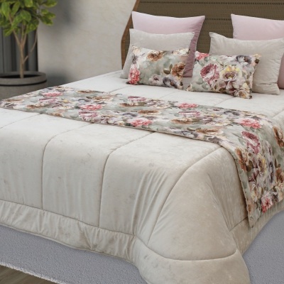 Cama com edredão bege e almofadas floridas