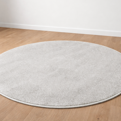 Tapete redondo cinza claro sobre chão de madeira clara