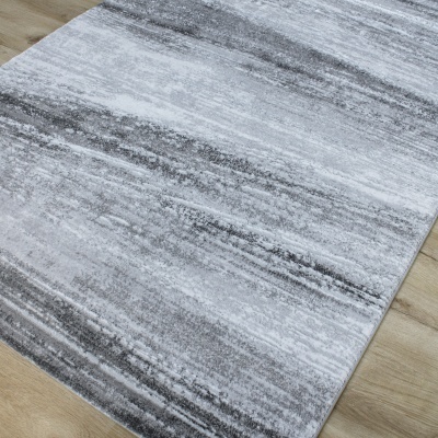 Tapete cinza abstrato sobre chão de madeira clara