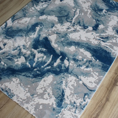 Tapete decorativo abstrato azul, cinzento e branco no chão de madeira