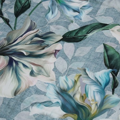 Tecido floral azul com grandes flores e folhas em várias tonalidades.