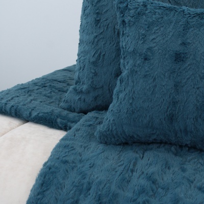 Almofadas e manta de tecido felpudo azul sobre sofá ou cama clara