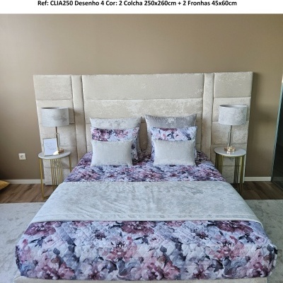 Cama com cabeceira cinza, colcha e fronhas florais roxas e cinza, mesas de cabeceira com abajures cinza