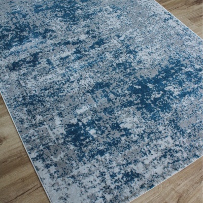 Tapete azul e cinza com padrão abstrato sobre chão de madeira clara