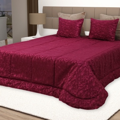 Cama de casal com colcha e almofadas vermelhas e bege em quarto moderno