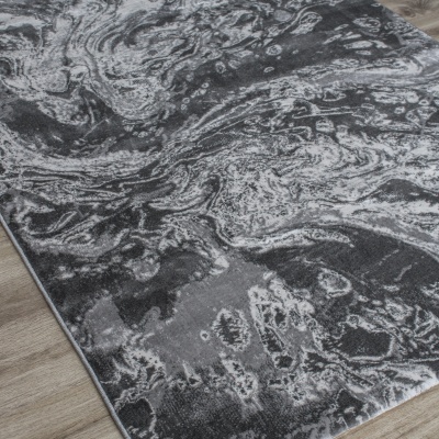 Tapete cinza e branco com padrão abstracto sobre chão de madeira