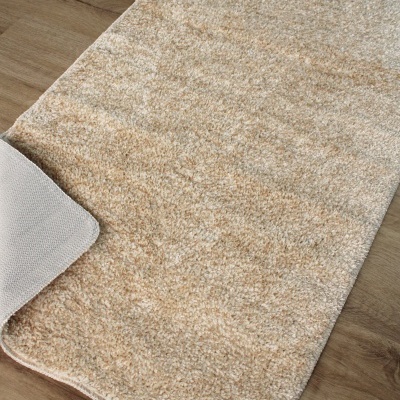 Tapete bege felpudo com canto virado em piso de madeira clara