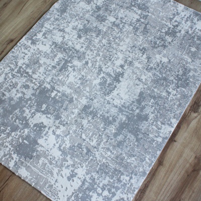 Tapete cinza e branco com padrão abstrato sobre chão de madeira