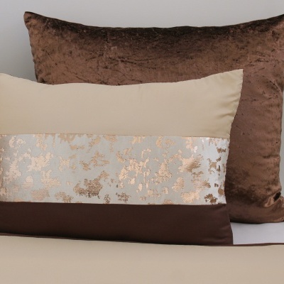Almofadas decorativas em tons castanho e bege com detalhes metálicos