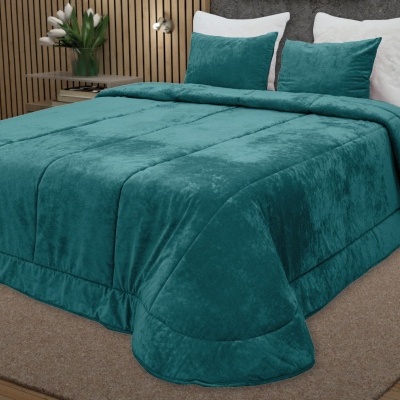 Edredão verde-azulado aveludado com almofadas na mesma cor numa cama branca em quarto moderno