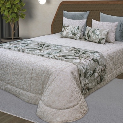 Colcha bege com faixa floral e almofadas decorativas em cama com cabeceira de madeira